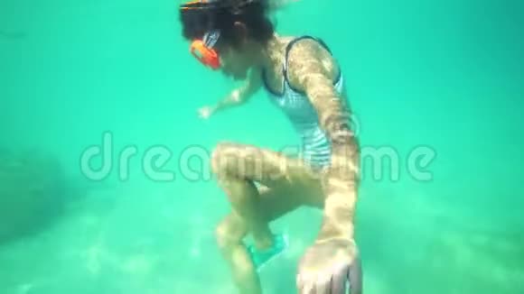 戴着水下面具的女孩在水下游泳看着水下世界和热带小鱼视频的预览图