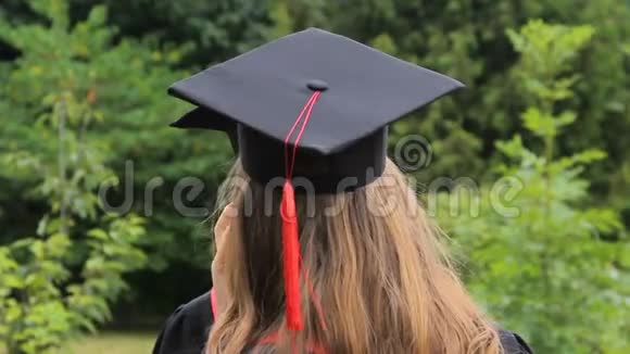 戴着毕业帽和流苏的女性朋友在学院附近聊天视频的预览图