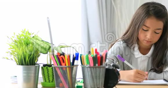 快乐的学校女孩看着相机在日托所用彩色铅笔画画视频的预览图