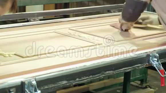 一个人一个工人从灰尘中清理一个木制的空白一扇门生产室内木门视频的预览图