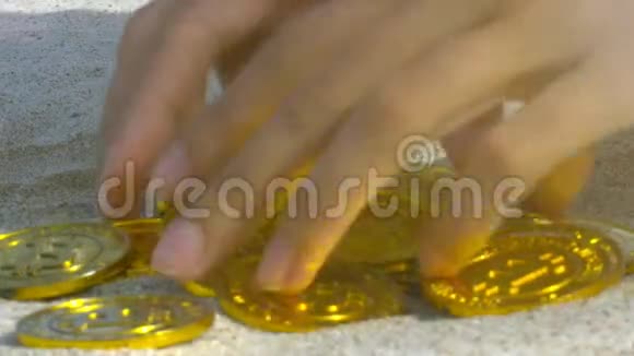 女孩的手从沙洞大洞中的挖掘中取出金币视频的预览图
