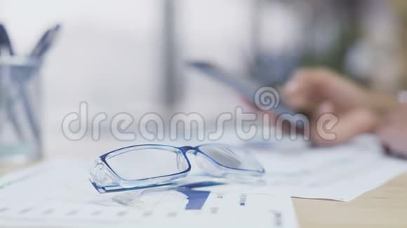 桌子上躺着眼镜智能手机上的女人滚动页面办公室休息视频的预览图