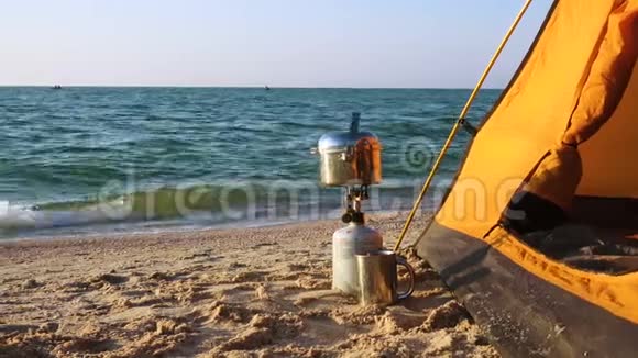 在沙滩上靠近帐篷的带食用锅的野营炉视频的预览图
