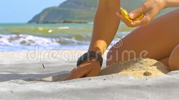 女孩在海滩特写镜头中从沙滩上挑选比特币视频的预览图