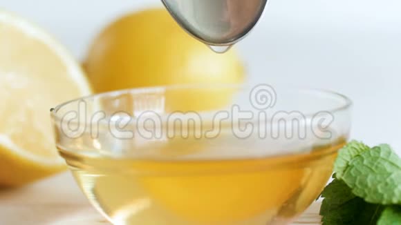 在白色的木桌上用勺子慢慢滴出蜂蜜在玻璃罐子里视频的预览图
