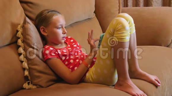 在客厅内部使用手机坐在沙发上的少女视频的预览图