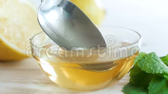 从金属勺子中慢慢滴出的蜂蜜在桌上的玻璃罐中的宏观镜头视频的预览图