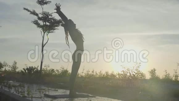 日出时在公园慢动作做瑜伽练习的女人剪影视频的预览图