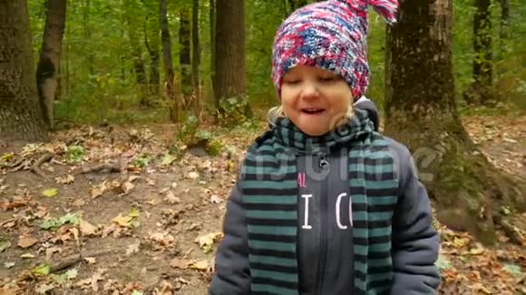 戴帽子和围巾的女孩的秋天肖像孩子在森林里散步视频的预览图