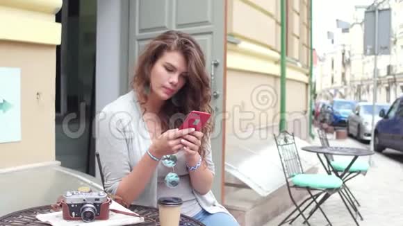 坐在欧洲城市街头咖啡馆的漂亮年轻女人视频的预览图