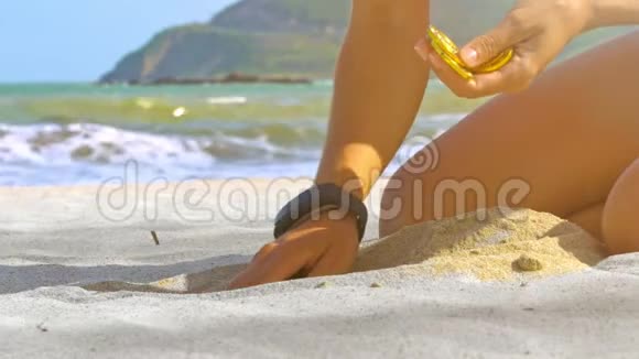 少女手在海洋特写镜头中从沙滩上挑选金币视频的预览图