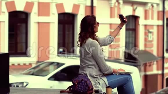 年轻漂亮的旅游女人坐在栏杆上自拍视频的预览图