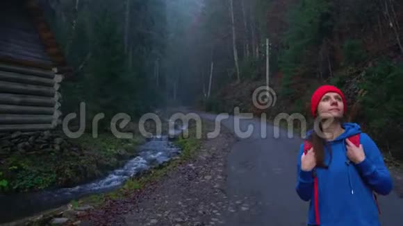 女旅行者背着背包在河边的山路上行走欣赏周围的风景视频的预览图