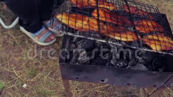 在帐篷附近一个女人用鱼把烤架翻过来男人在烤架里搅动煤视频的预览图