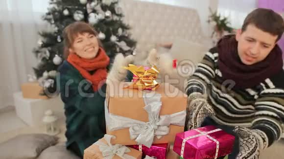 男孩和女孩从一堆礼物中拿出礼物向观众炫耀圣诞节的主题视频的预览图