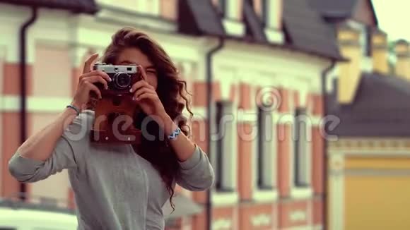 迷人的旅游女孩带着旧相机在街上拍照视频的预览图