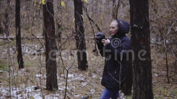 女孩摄影师走在秋天的森林里拍摄大自然的照片电影镜头慢动作第一场雪视频的预览图