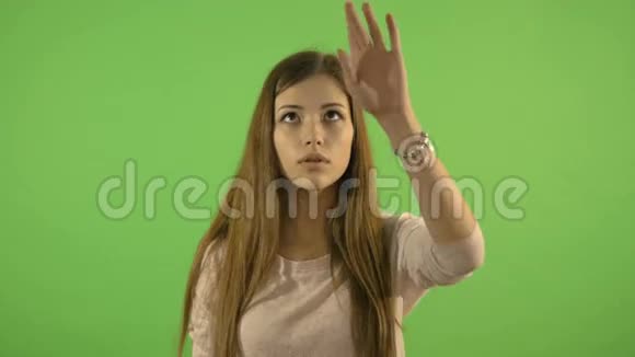 美丽的女孩在想象中的屏幕上显示手势寻找和搜索信息在绿色的背景下视频的预览图
