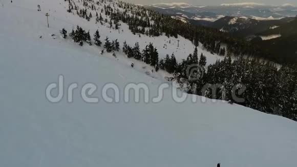 在一片森林和一个旅游村庄的背景下滑雪者在滑雪坡上的全景视频的预览图