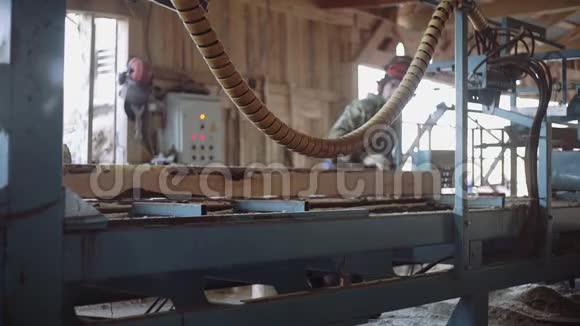 伐木工人在头盔切割木材原木工业锯机视频的预览图