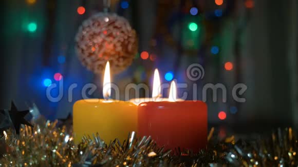 新年蜡烛特写和圣诞装饰品有彩色灯光的模糊背景视频的预览图