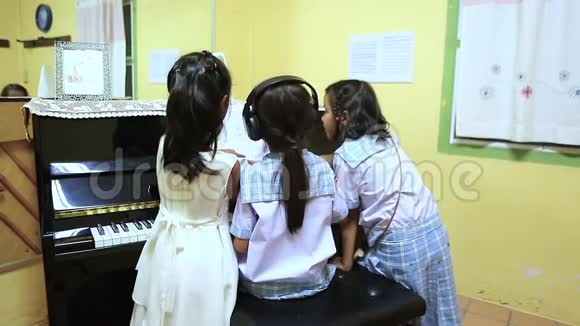 三个亚洲学校的女孩在书房里弹钢琴视频的预览图