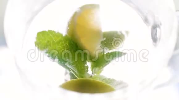 从顶部观看柠檬片冰块和薄荷叶旋转和漂浮在大玻璃上视频的预览图