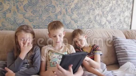孩子们在平板电脑上玩耍在家里坐在沙发上视频的预览图