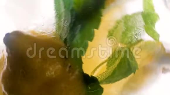 柠檬片冰块和薄荷叶混合在一杯柠檬水中的4k镜头视频的预览图