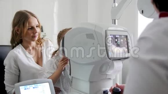 母亲和女儿眼科医生的小女孩诊所的验光师检查小孩视力视频的预览图
