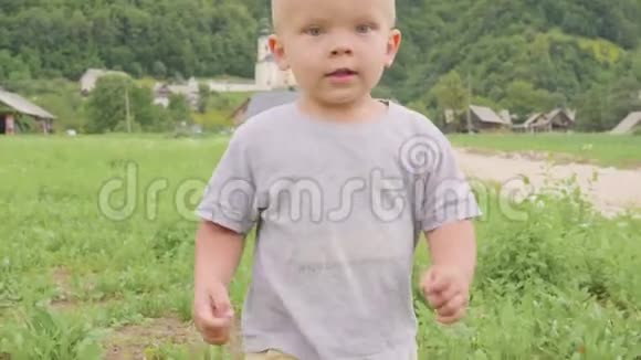 小男孩站在绿色的草地上奔跑玉米或玉米晴天在自然的蓝天和视频的预览图