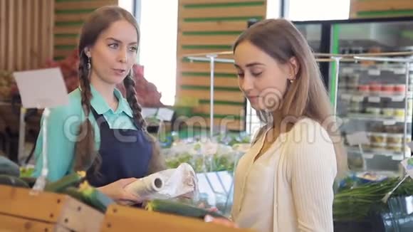 年轻女子选择新鲜黄瓜站在室内商店视频的预览图