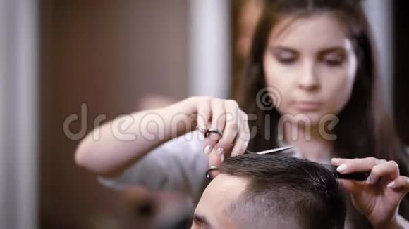 女理发师用剪刀和梳子理发男性顾客坐在椅子上有选择性的聚焦和紧密视频的预览图