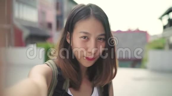 开朗美丽的年轻亚洲背包客博主女士在唐人街旅行时使用智能手机自拍视频的预览图