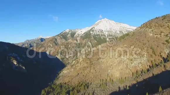 沿山一侧的空中景观可以看到白雪皑皑的山顶和下面陡峭的山谷视频的预览图