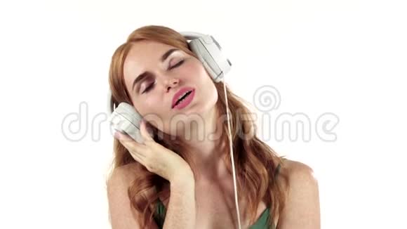 女孩通过耳机听她最喜欢的音乐白色背景慢动作视频的预览图