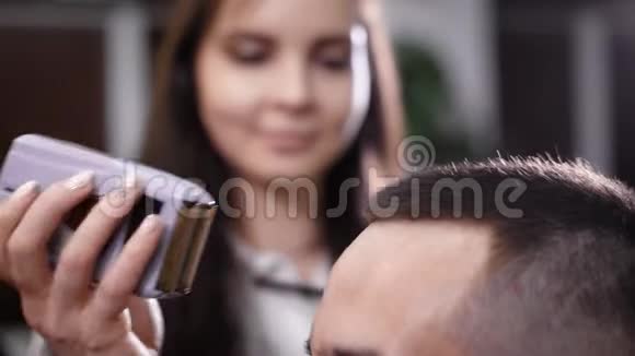 女理发师用电动剪发器修剪头发男性顾客有选择的焦点和近距离观察视频的预览图