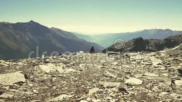 慢动作放大到孤独的女人坐在岩石地形和观看广阔的视野在山谷视频的预览图