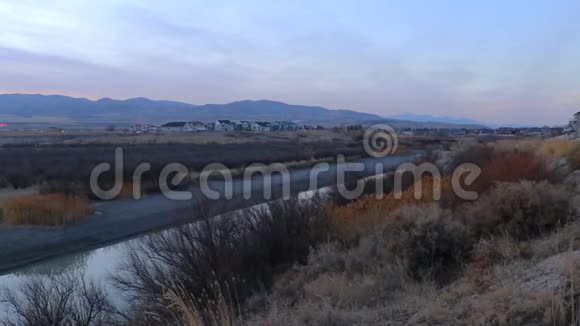 黄昏时分远处山脉的夕阳随着摄像机的旋转而放大一条河流的全景视频的预览图