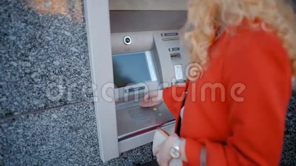 漂亮的女人从自动取款机上拿起她的银行卡取出钱视频的预览图