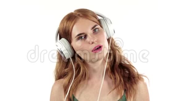 女孩通过耳机听她最喜欢的音乐白色背景慢动作视频的预览图