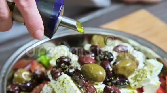 特写一只雌性手浇灌鲜纯素希腊色拉橄榄油天然食物健康生活方式视频的预览图