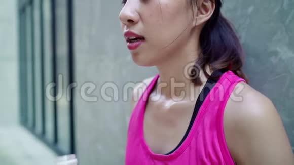 慢动作健康美丽的年轻亚洲跑步女子饮水因为在街上跑步后感到疲倦视频的预览图