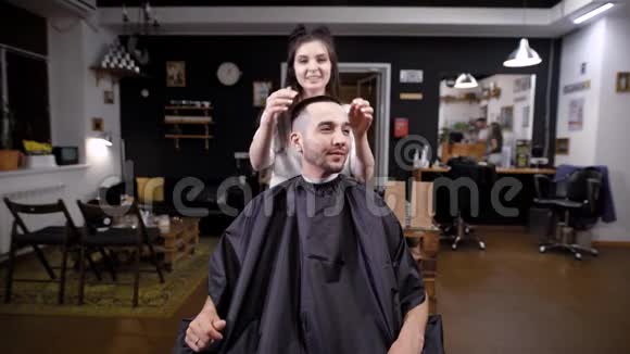 男顾客参观理发店和女理发师一个人看着镜子里的自己完成的工作他的视频的预览图