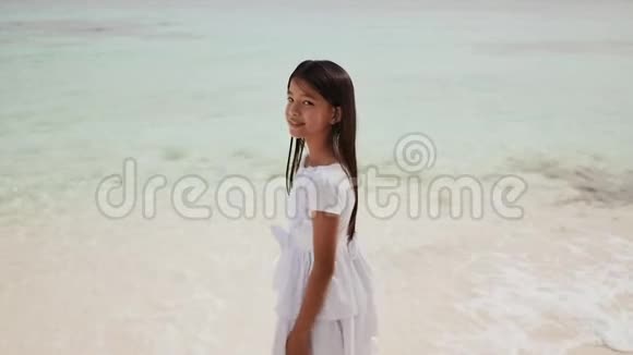 一个穿着白色裙子的迷人的菲律宾女学生正沿着白色沙滩散步享受热带风光视频的预览图