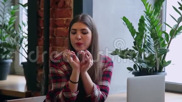 一位漂亮的女商人坐在一张桌子旁在咖啡馆里拿着笔记本电脑画着她的指甲视频的预览图