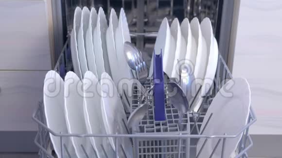 男人卸下洗碗机从篮子里拿出白色的餐具和餐具视频的预览图