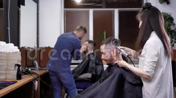 在工作的理发师集体理发店的工作场景坐在椅子上的顾客视频的预览图