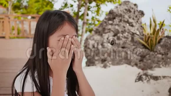 一个背着背包的菲律宾女学生坐在热带海岸附近哭泣悲伤的心情视频的预览图