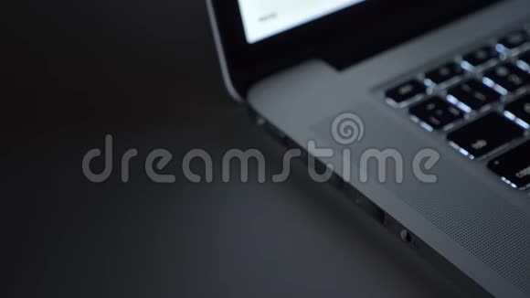 男性手的特写镜头快速地将usb线插入黑桌背景上的笔记本电脑视频的预览图